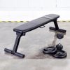 Vitox Fitness-Foldable flat bench VB105 with a padded seat and sturdy metal frame, shown in a folded position for easy storage. The bench features non-slip feet for stability and is compact for convenient portability.