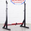 Vitox Fitness Squat rack: A minimalist black and red squat rack featuring two vertical posts with adjustable barbell holders. The frame includes a stabilizing horizontal support bar at the base with adjustable width, allowing for customization to accommodate various barbell exercises like squats and bench presses. The compact design is ideal for home use, with non-slip feet ensuring stability.